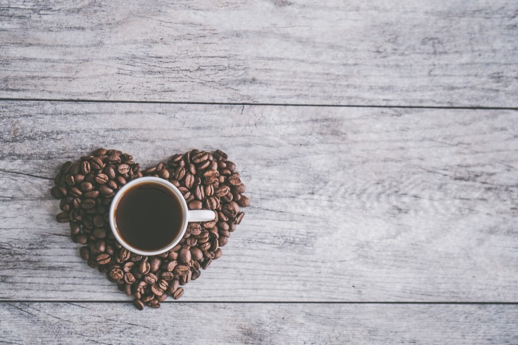 heart shaped coffee beans and a cup of coffee